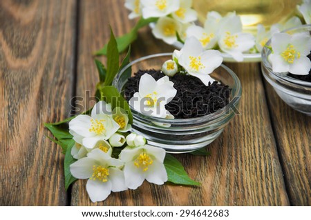 Dry black jasmine tea with jasmine flowers in bowls on a wooden background