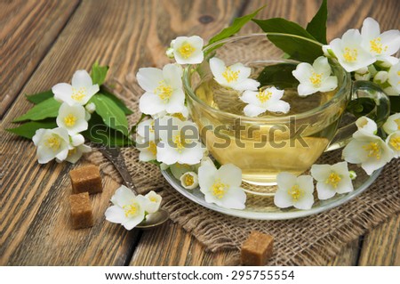 A cup of jasmine tea with jasmine flowers on a wooden background