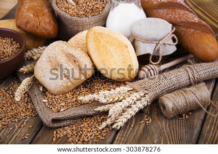 Different bread, wheat, milk and honey on the wooden table