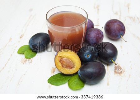 Fresh plum juice with plums on a white wooden background