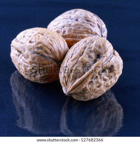 Three walnuts over a black reflecting surface