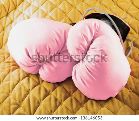 Pink boxing gloves over a soft yellow background