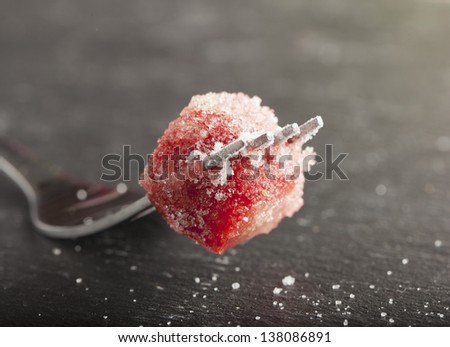 Piece of strawberry full of sugar on a fork