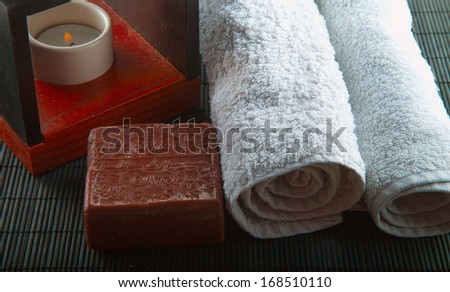 Brown soap, candle and towel over wooden background