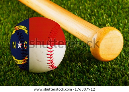 Baseball with North Carolina flag and bat over a background of green grass