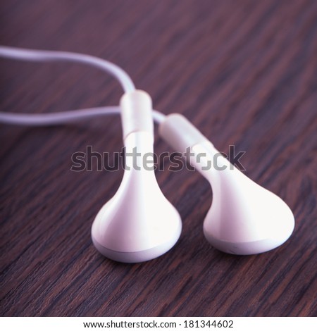White earphones over a dark wooden background