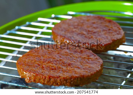 Hamburgers over a bbq, focus over low part of first hamburger