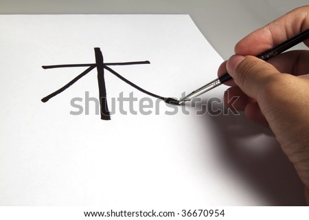 Male hand writing Chinese ideogram meaning the word tree