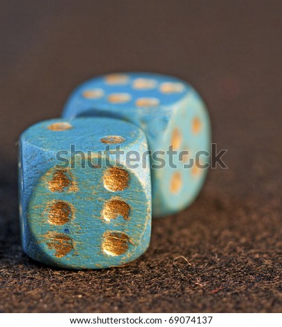 Old blue dice with golden numbers over black background