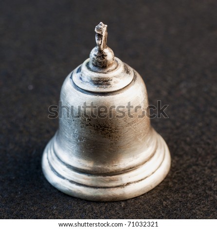 Little silver bell over black background
