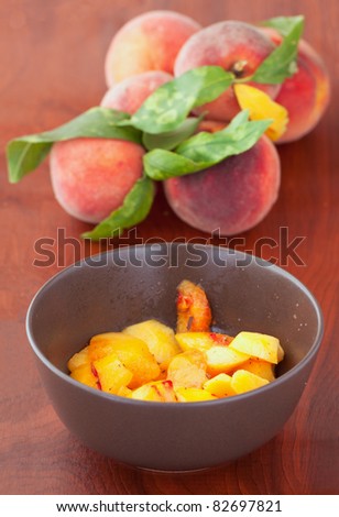 Cup of slices of peaches with sugar and cinnamon, with peaches on the back