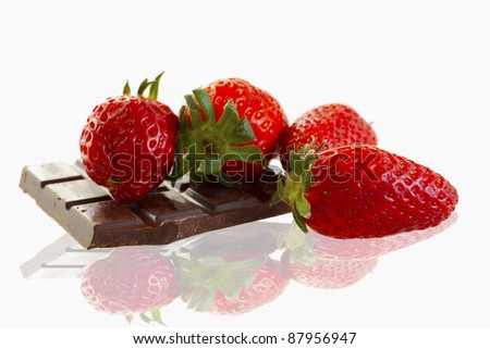 Four strawberries laying on a piece of chocolate, over white
