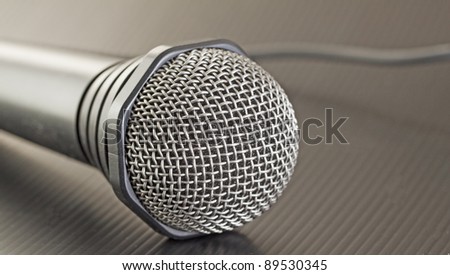Gray microphone with wire over black background
