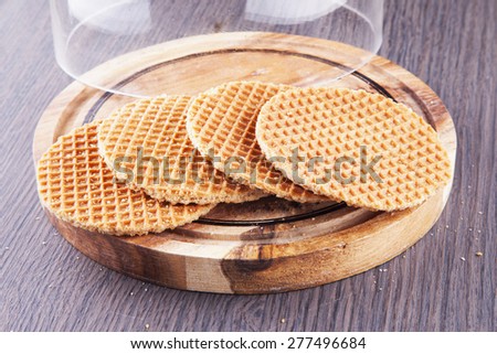 Round waffel over wooden plate, with bell jar, horizontal image