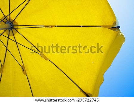 Yellow umbrella for beach seen from below, blue sky, horizontal image