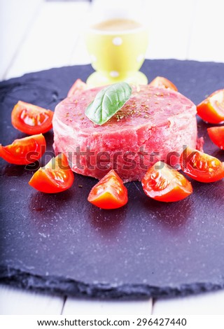 Tartare raw meat with tomatoes and egg cream over black stone plate, vertical image