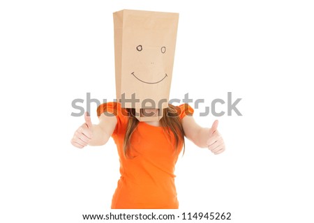 young girl in smiling ecological paper bag on head with thumbs up, white background