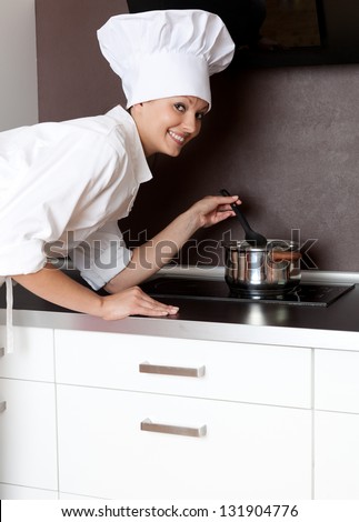 beautiful female chef in whte uniform cooking in kitchen