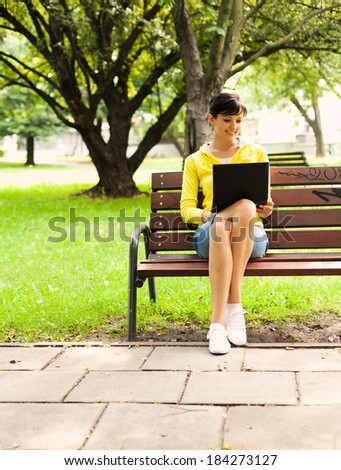 young woman with laptop in the park, full lenght