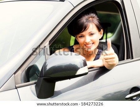 successful young woman in the car with thumb up