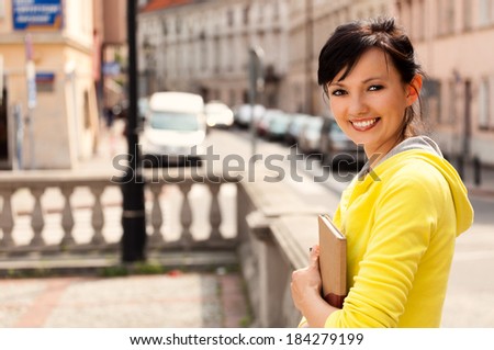 student girl in the city, keeping book, smiling