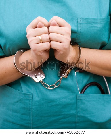 Female body in green, medical clothes, from stethoscope, in handcuffs showing sign fig hands