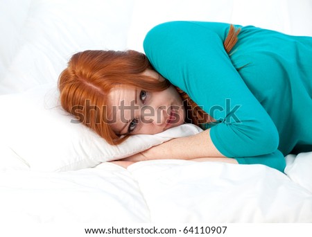 beautiful young woman in turquoise blouse lying on white bedding
