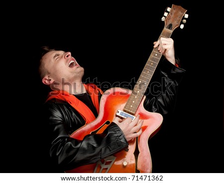 young man playing on orange electric guitar, black background