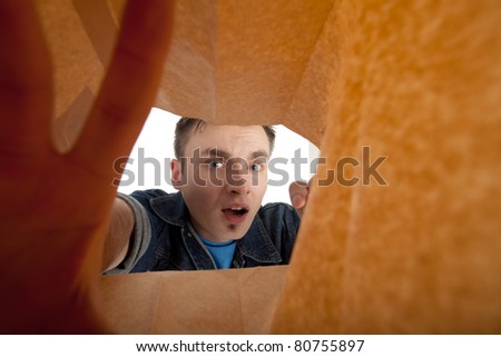 frightened young man looking to paper bag