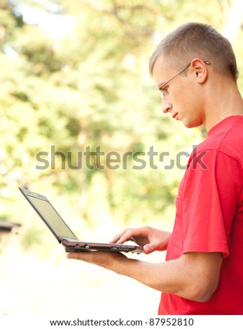 male student working on laptop in the park