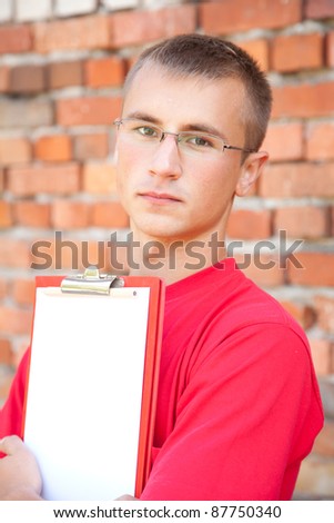 teenage male student with blank clipboard, outdoors