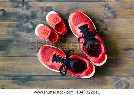 Two red sport running shoes or sneakers of mother or father and child on wooden background,use for father\'s day or mother\'s day or family\'s day with sport concept