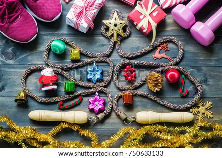Fitness, healthy and active lifestyles greeting card concept, dumbbells, sport shoes, skipping rope or jump rope  in the form of christmas tree with Christmas decoration on wood background retro tone.