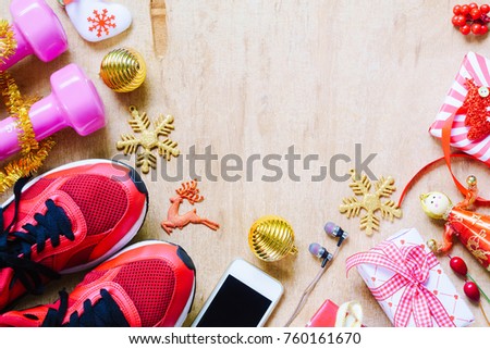 Fitness, healthy and active lifestyles love concept, dumbbells, sport shoes, skipping rope or jump rope and smart phone with Christmas decoration items on wood background.