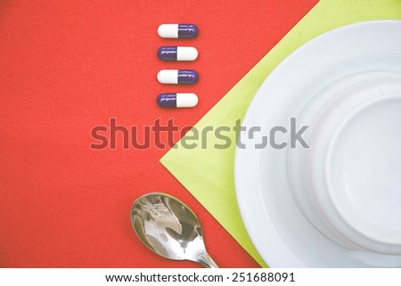 A cup standing on a colorful table with some colored pills on the cup side