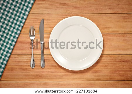 Empty Plate, Fork, Knife and Table Cloth on wooden background. Top View with Text Space