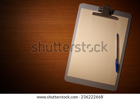 Clipboard with Blank Paper and Blue Pen on Wooden Table. Top View of Desk with Copy space for text or image