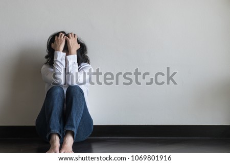 Panic attack woman, stressful depressed emotional person with anxiety disorder mental health illness, headache and migraine sitting feeling bad with back against wall on the floor in domestic home