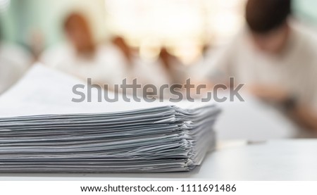 Exam answer sheet or application paper blurry view on table in examination room with blur education background of school university students taking exam test writing answer in seat row with stress