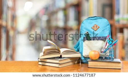 Back to school concept with school books, textbooks, backpack and stationery supplies on classroom desk with library or class background for educational new academic year begin or study term start