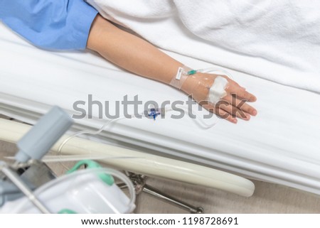 Patient on hospital bed in medical in-patient ward resting with iv fluid intravenous drop or saline drip through hand injection for nursing care or healthcare recovery treatment from illness concept