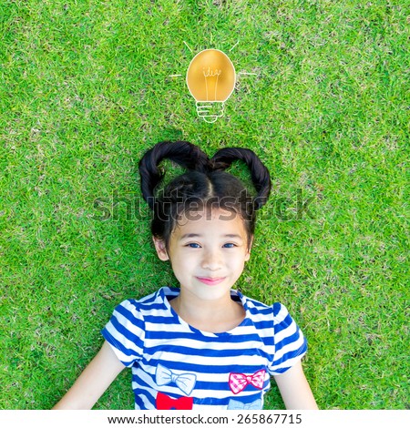 An asian  kid with heart-shaped hair on grass with a golden egg in light bulb shape over the girl\'s head: Kid\'s idea and imagination