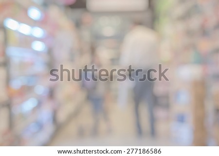 Blurred abstract background of people shopping in super market : Shoppers in grocery store walking in a gangway : Walkway with full with goods and products on shelves in super market