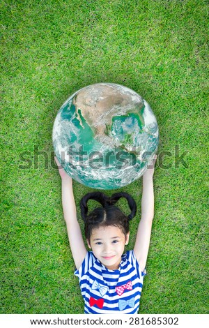 Smiling lovely happy kid holding green planet lying on grass floor : Healthy little child love green planet : Earth day concept of saving green environment: Elements of this image furnished by NASA