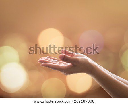 Empty open hands with palms up and candle lights bokeh in warm gold color tone: Female prayer praying warm tone background: Peace of mind mental health concept: Humanity aid: Easter Holy spirit week