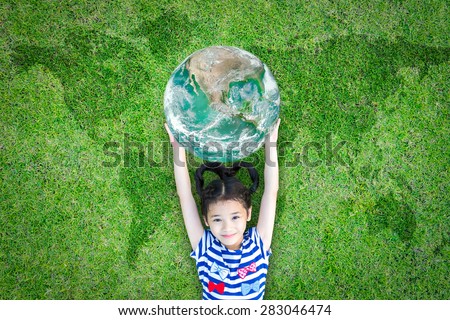 Smiling happy healthy little asian kid holding green globe lying on world global map grass: World environment day CSR concept saving eco green sustainable ecosystem: Element of image furnished by NASA