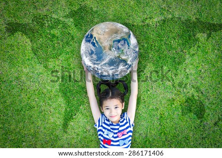 Happy lovely kid carrying a blue marble planet globe lying on the world map grass : International youth concept : Children in green environment concept: Elements of this image furnished by NASA