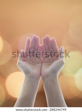 Empty female open human hands with palms raised up among candle lights bokeh  in natural warm gold color tone background : Pray for spiritual support and helping concept