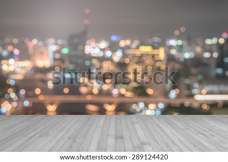 Wood floor in light grey color tone with blurred abstract background of Bangkok night lights city view on riverfront with bokeh with light flare : Wooden table  with blur background of cityscape