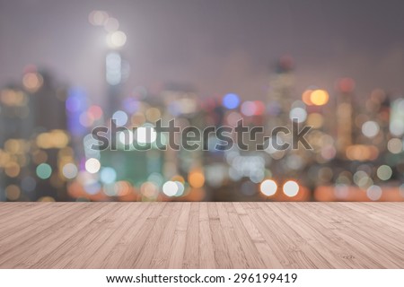 Wood floor in light red brown color tone with blurred abstract background of Bangkok night lights downtown city view with bokeh with light flare : Wooden table with blur background of cityscape